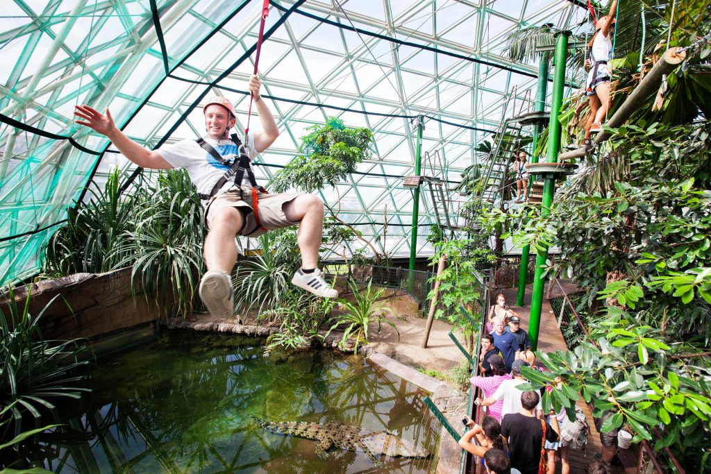 man zip lining over crocodile